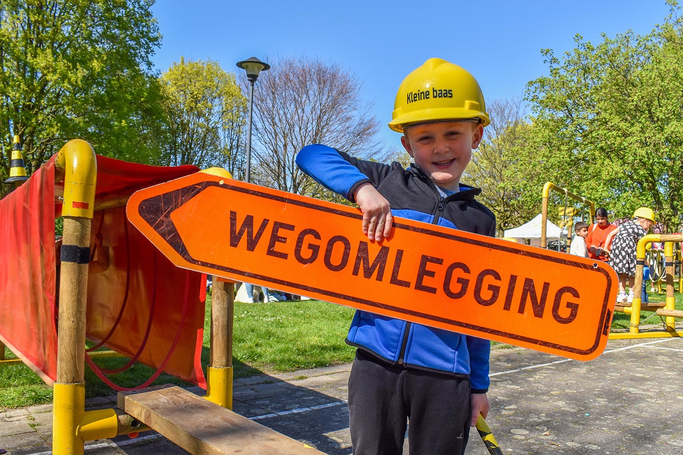 kind met werkhelm en bord met wegomlegging op