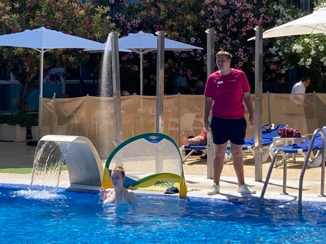 Stagiair helpt bij de activiteiten aan het zwembad van een hotel