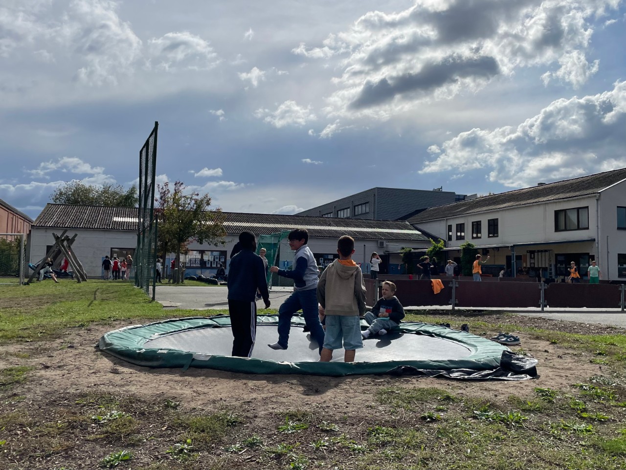 Leerlingen op de trampoline op de blauwe speelplaats
