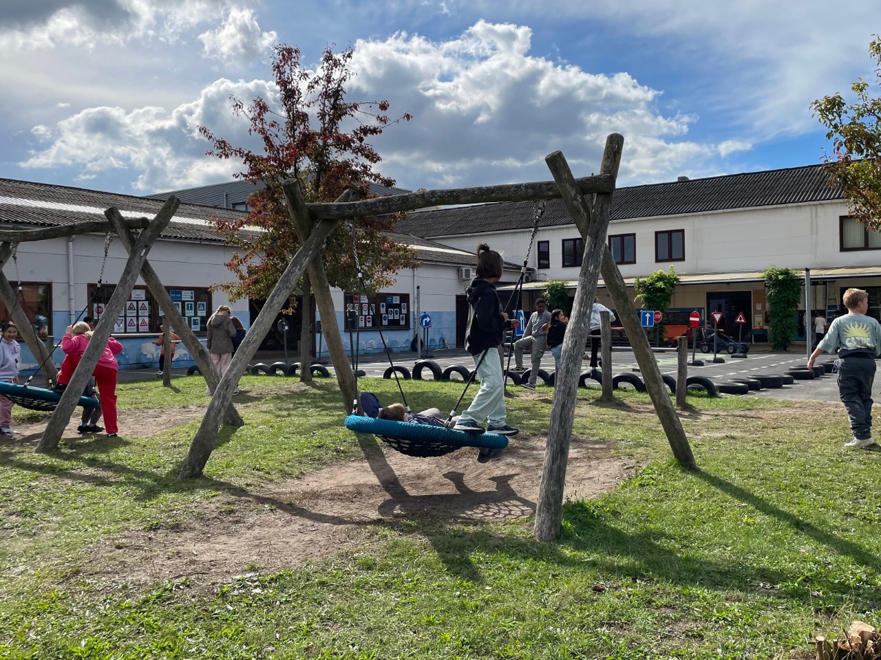Leerlingen op de schommel op de blauwe speelplaats