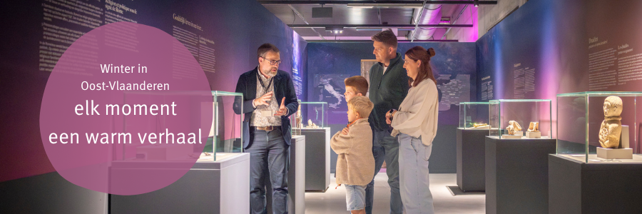 winterbanner: gezien luistert gefascineerd naar de  uitleg van een gids en archeocentrum Velzeke