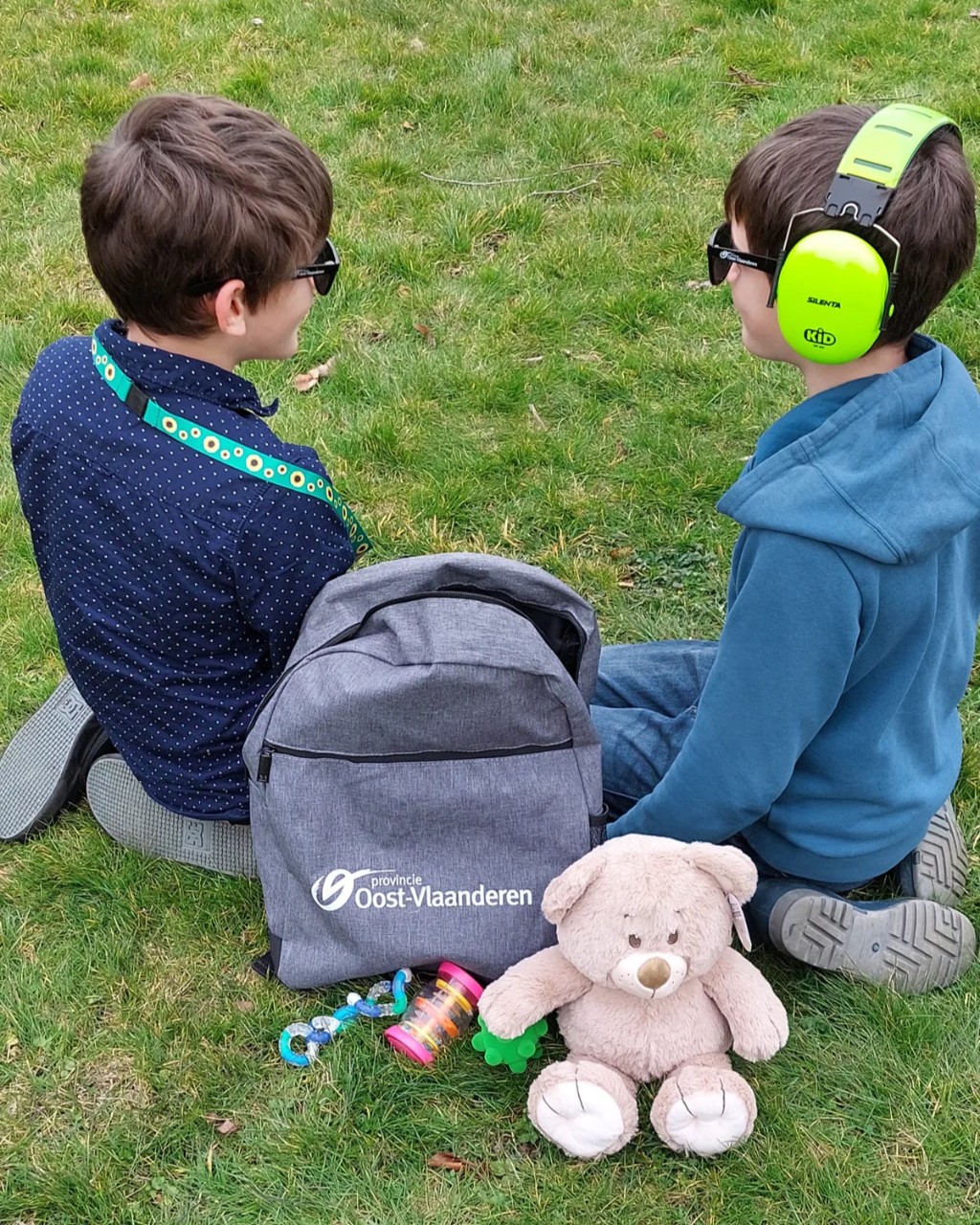 foto van twee jongens bij de inhoud van een snoezelrugzak zoals zonnebril, koptelefoon en een verzwaringsbeer