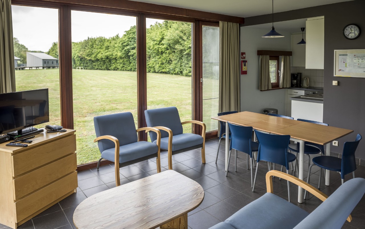 vakantiewoning 6 personen binnenkant huisje met zetels, tafel en stoelen en open keuken