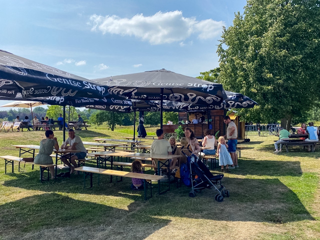 sfeerbeeld van mensen onder parasols op de zomerbar Bar Panorama in Puyenbroeck 