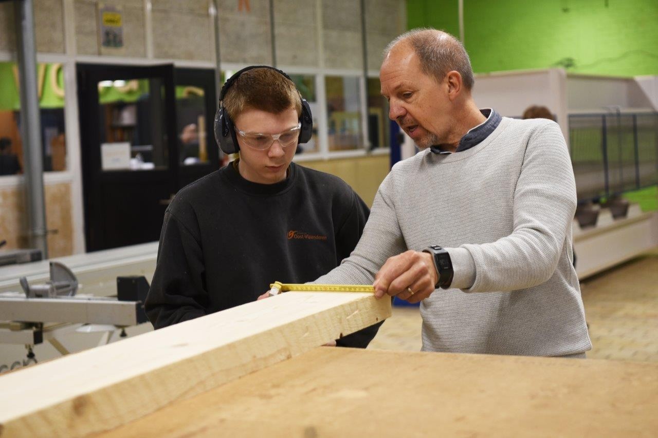 leerkracht en leerling meten hout in les houtbewerking