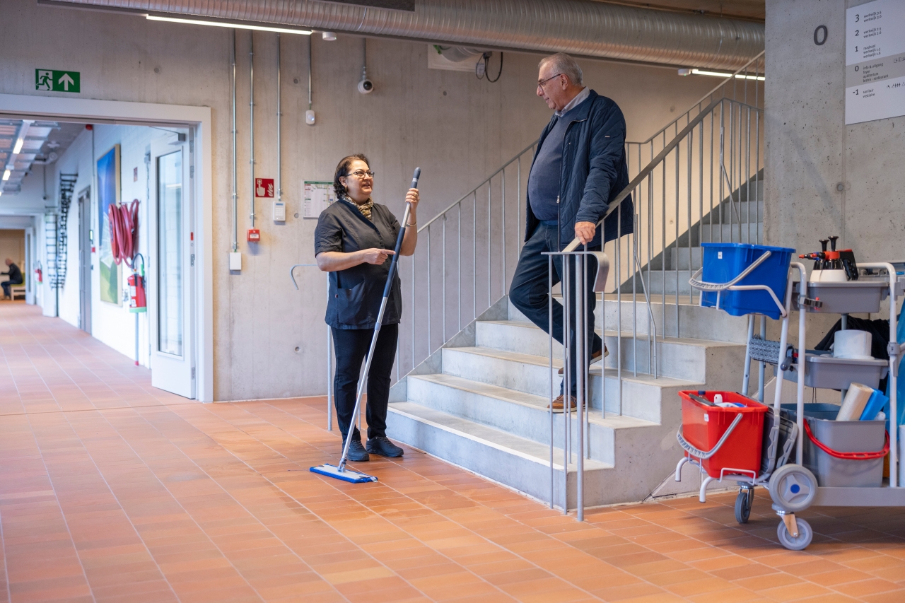 deskundige schoonmaakbeheer in gesprek met collega op werkvloer